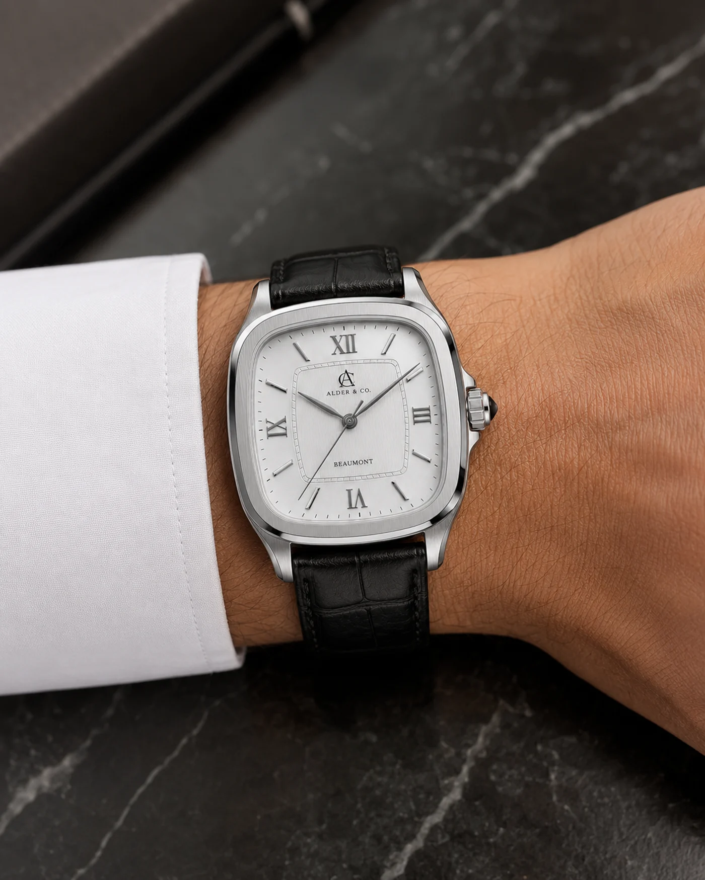 The Beaumont worn on the wrist beside a dark marble surface